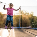 Young girls jumps on a netted trampoline.